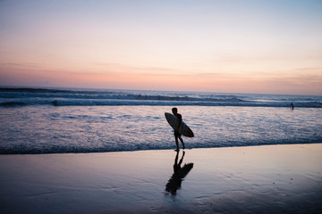Silhouette of surfer on a Bali beach at sunset