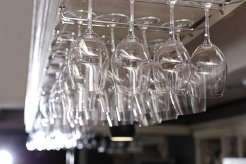 Set of empty clean glasses on bar racks