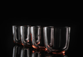 Empty colorful whiskey glasses on black background