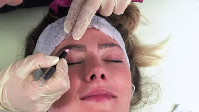Young girl make permanent makeup. Eyebrow Microblading