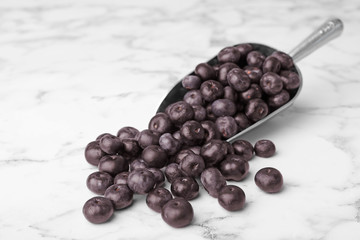 Metal scoop of fresh acai berries on marble table, space for text