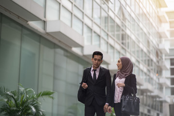 Two asian business partner walking together smiling at the office street