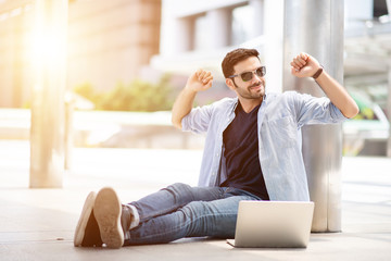 Young self-employed are stretched with a laptop while sitting in the center of the work.