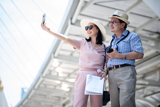 Elderly couple using a cell phone self-portrait while traveling abroad happily.