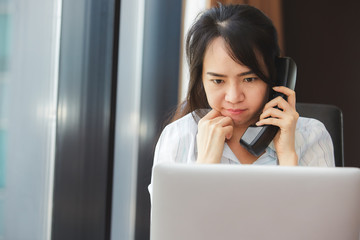 Happy asian business woman talking the phone at the working place.
