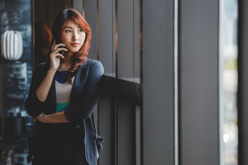 Young attractive asian business woman using mobile phone in  working place.