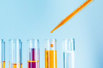 Laboratory test tubes with red and yellow liquids on light blue background