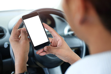 Cropped shot view The driver uses the phone while driving. Modern smart phone with round edges. Isolated screen for mockup. Car navigation display in background. 