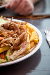 Mann bei gemeinsamer Mittagspause mit Döner Kebab Teller mit Pommes, Salat, Scharf und Knoblauch Sauce