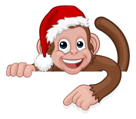 A Christmas monkey animal cartoon character in a Santa hat behind a sign peeking over a sign and pointing at it