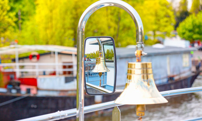 Small bronze bell on a sailing ship and its reflection in the mirror with sea background