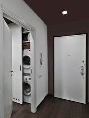 interior shot of a entrance with main door overlooking on the dryer machine and the washing maschine the floor is made of wood