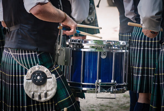 Closeup of the traditional Scottish drum and the hands of a drummer wearing kilt in Scottish band playing outdoors