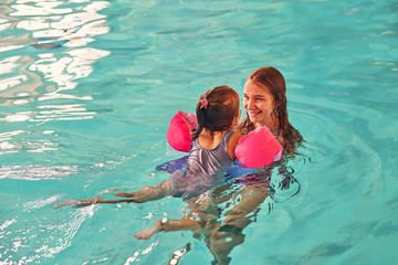 Woman playing with girl in swimming pool