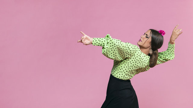 Medium shot flamenca performing floreo on pink background
