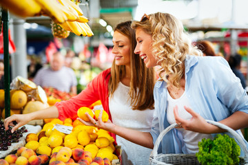 Young happy women shopping vegetables and fruits on the market