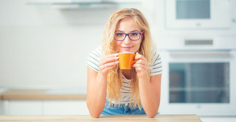 Cup of coffee in hand of happy young woman. Attractive girl drinking morning tea