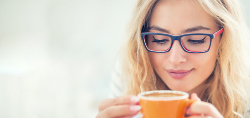 Cup of coffee in hand of happy young woman.