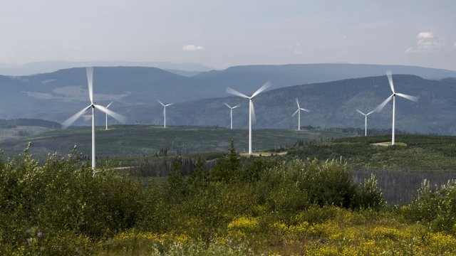 Wind turbines on forested hills on smokey day 4K time lapse