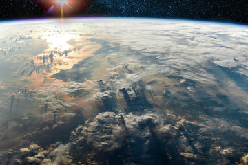Clouds with long shadows above the Earth and sunlight reflection in the sea, Elements of this image furnished by NASA.