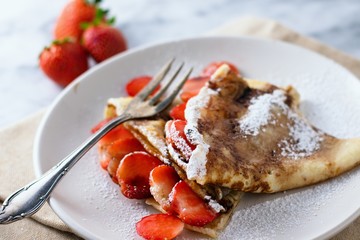 Triangle folded crepes with strawberries and powdered sugar