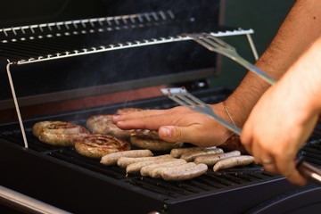 Male hands feeling the warmth and readiness of garden barbecue hot dogs