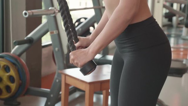 Attractive sport Asian woman using big triceps push down rope for workout bodybuilding in fitness gym. People lifestyles and muscular exercise. Sport activity and Healthy concept. 4K Footage video