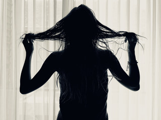 Woman with towel in front of a window and curtain.