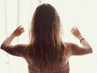 Silhouette of a girl while waking up in the room and holding curtain.
