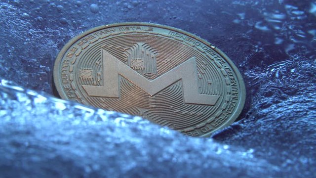 Golden Monero coin, online digital currency frozen in the blue ice. Concept of block chain, crypto market crash. Frozen crypto money, depreciation