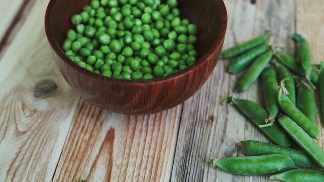closeup green peas in brown dish, on wooden table.