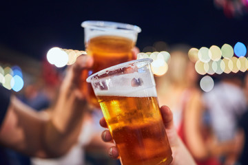 Friends drinking beer at night with de-focused lights in the background. Shallow focus.