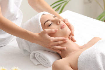 Fototapeta na wymiar Young woman having facial massage in beauty salon