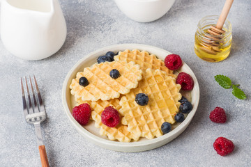 Corrugated waffle cookies with fresh raspberries and blueberries on a concrete background. Copy space.
