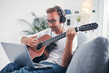 Obraz premium Man playing acoustic guitar in the living room.