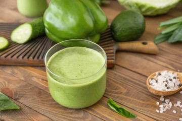 Glass of tasty smoothie with ingredients on table