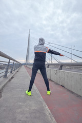 Sportsman working out / jogging on a big city urban bridge.