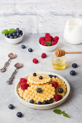 Corrugated waffle cookies with fresh raspberries and blueberries on a concrete background. Copy space.