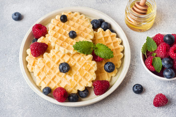 Corrugated waffle cookies with fresh raspberries and blueberries on a concrete background. Copy space.