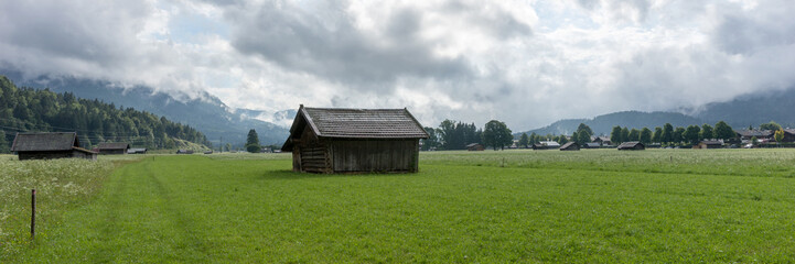 Fototapeta na wymiar Panorama landscape. Old wooden hut on alpine meadows with mountains in background