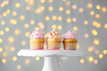 Tasty Birthday cupcakes on stand against defocused lights