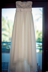 wedding dress hanging on a hanger in the window