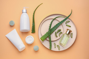 Cosmetic products with aloe leaves on color background
