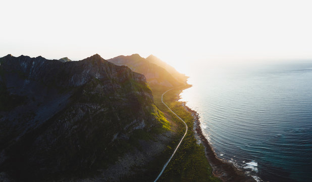 Sonnenuntergang mit Sicht auf Fjord in Norwegen und Stra&szlig;enverlauf unterhalb Bergkette 