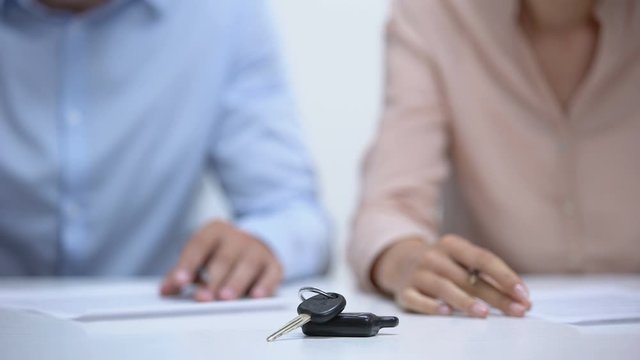 Car keys closeup, couple signing divorce documents about property division