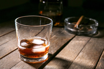 Glass of cold whiskey with ice on wooden table