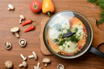 Breakfast, fried eggs in a pan with tomatoes and chili peppers