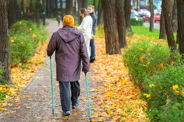 Senior woman enjoying nordic walking at beautiful colorful autumn park. Old age person doing pole...