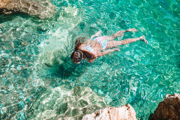 Happy little girl in snorkeling mask dive underwater with tropical fishes