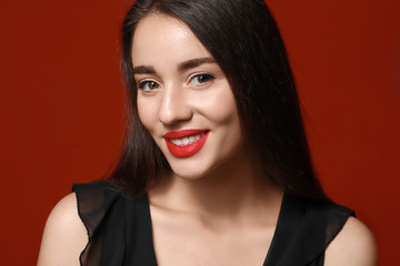 Beautiful young woman with bright lipstick on color background